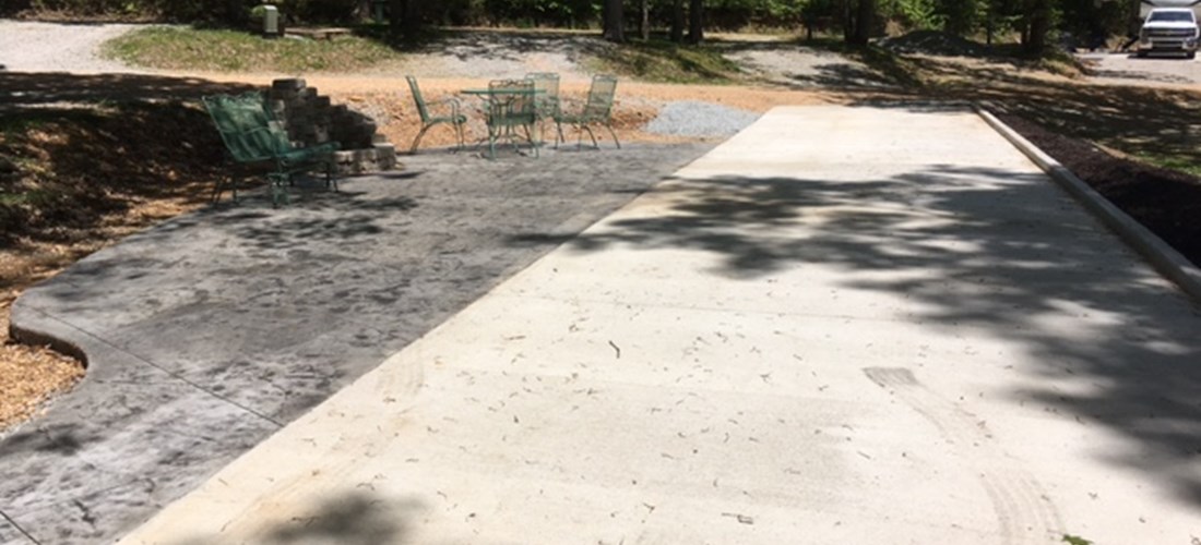 Patio Site with  concrete RV pad, concrete patio with stone fire pit, glider, table and 4 chairs and a Blackstone griddle.