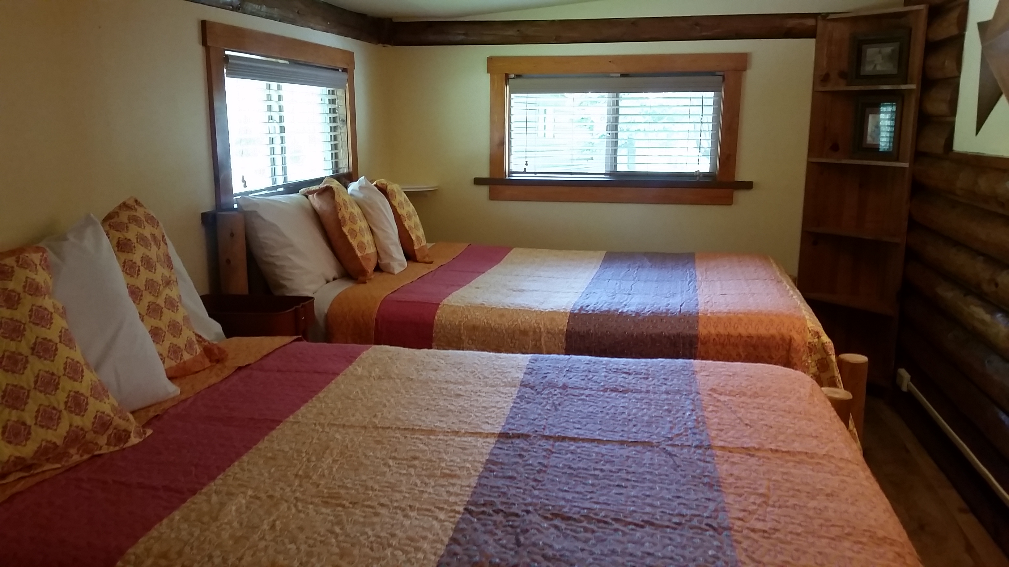 A cozy back bedroom offers 1 Queen & 1 Double log bed.