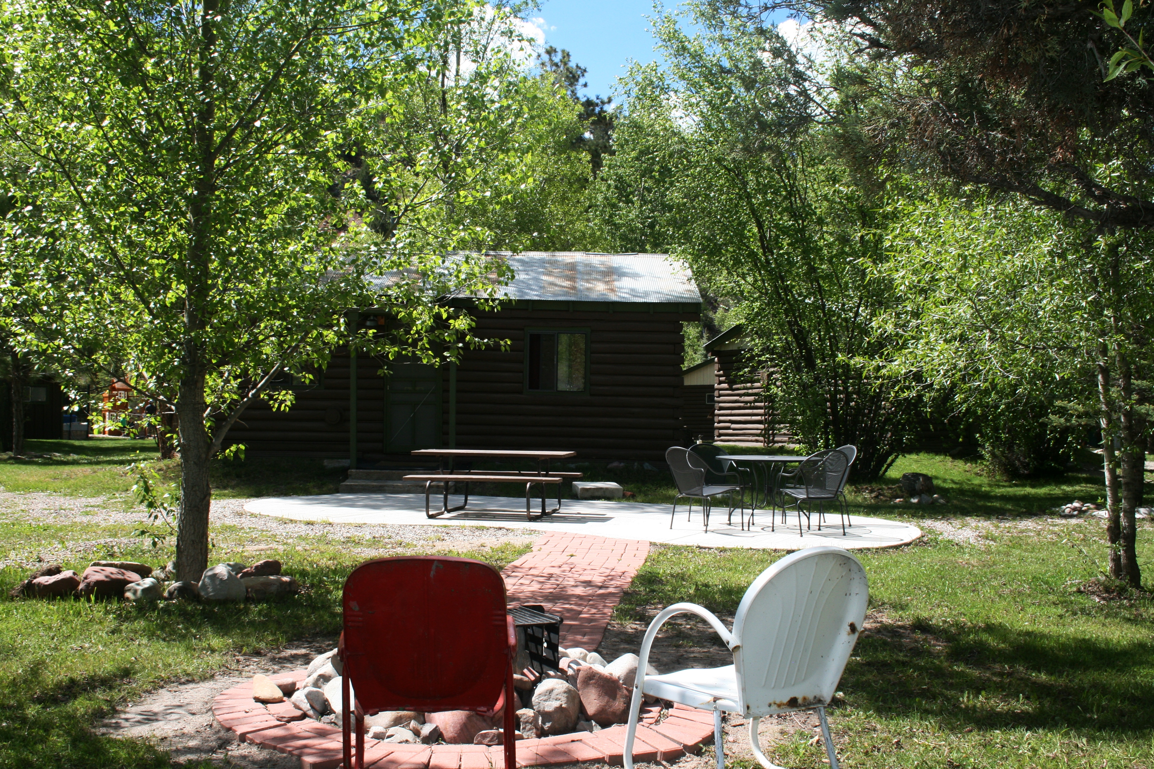Outdoor patio and firepit looking from the riverbank toward cabin 9