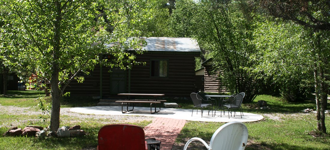 Outdoor patio and firepit looking from the riverbank toward cabin 9