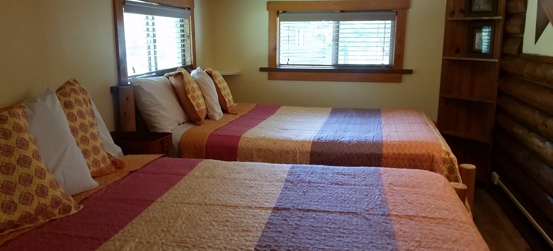 A cozy back bedroom offers 1 Queen & 1 Double log bed.