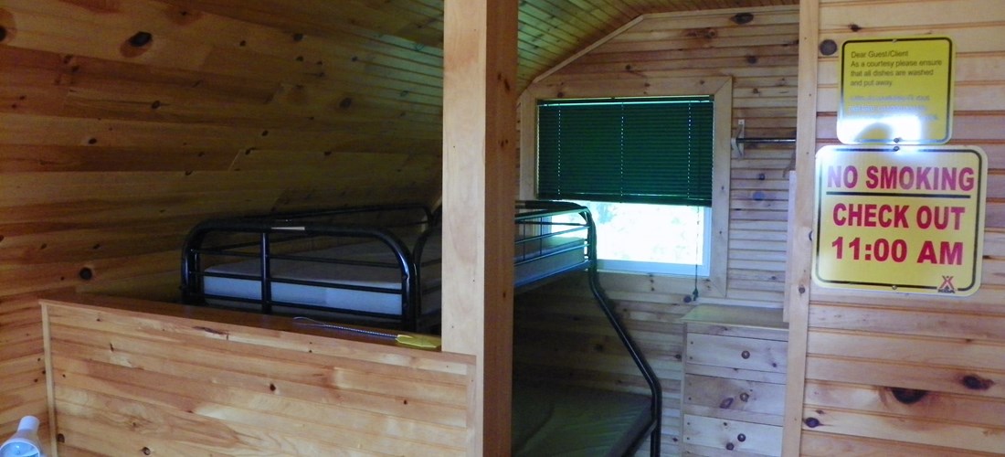 Deluxe cabin sleeping area, double bed with single on top.