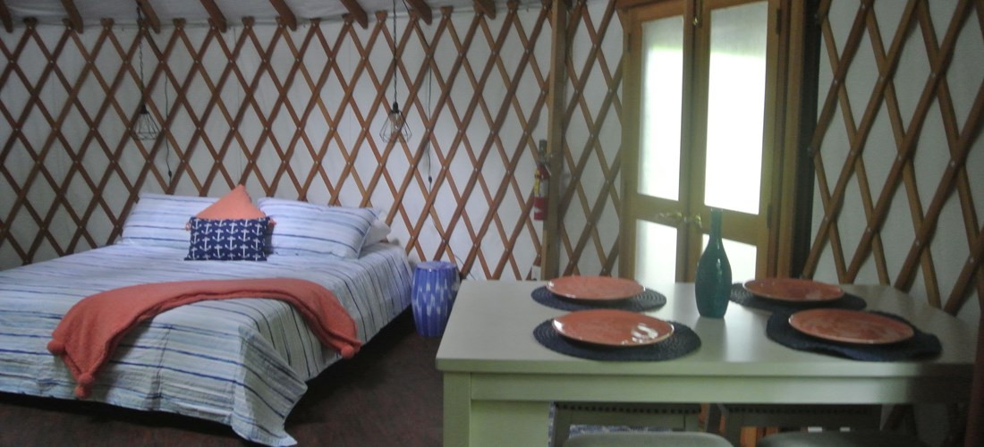 Bluegills Riverside Yurt: Photo features a queen size bed and bar-height dining table with 4 stools.
