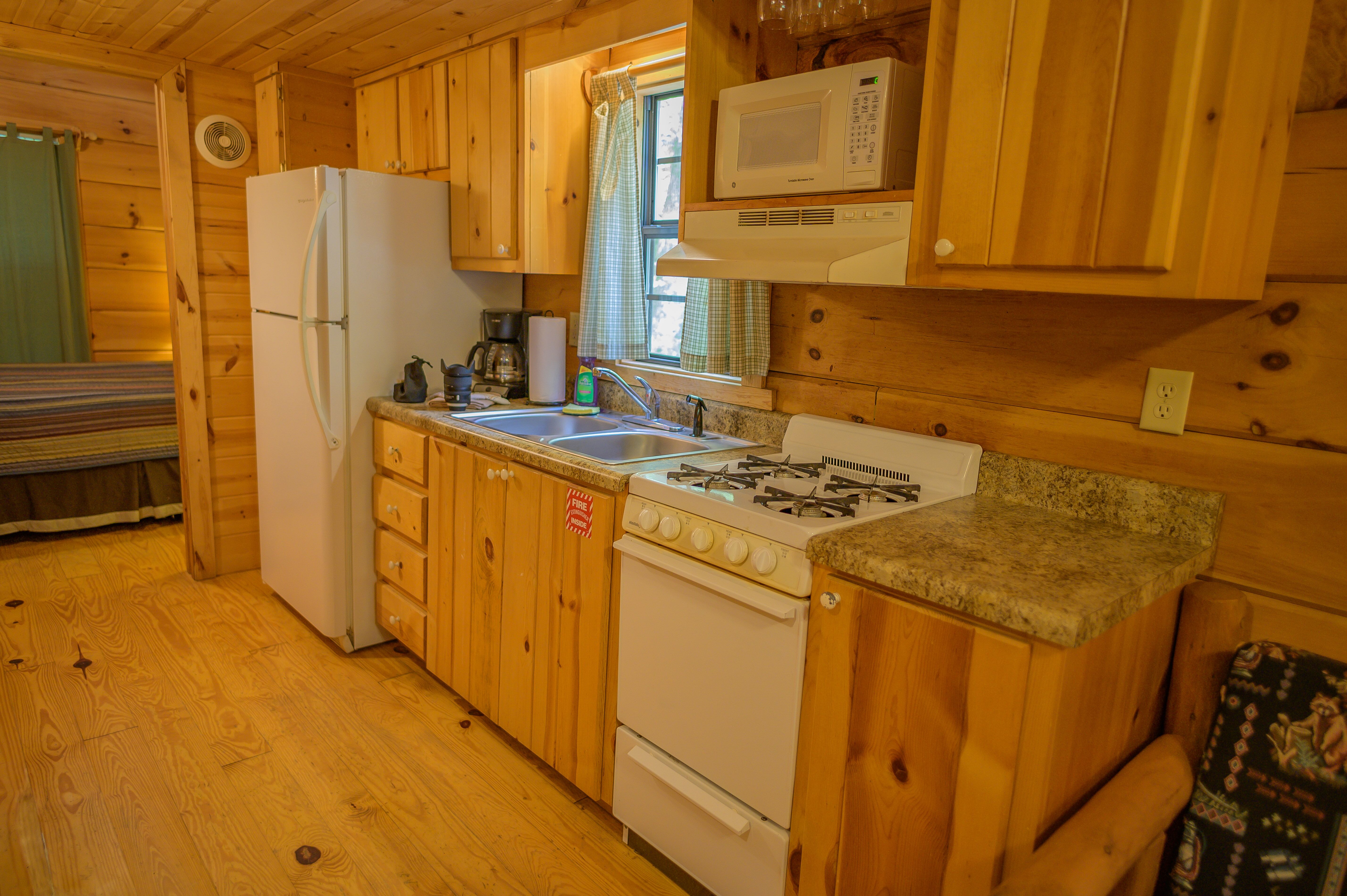 Galley Style kitchen of Deluxe Cabin. Full Fridge, gas stove and oven, microwave and dishes provided