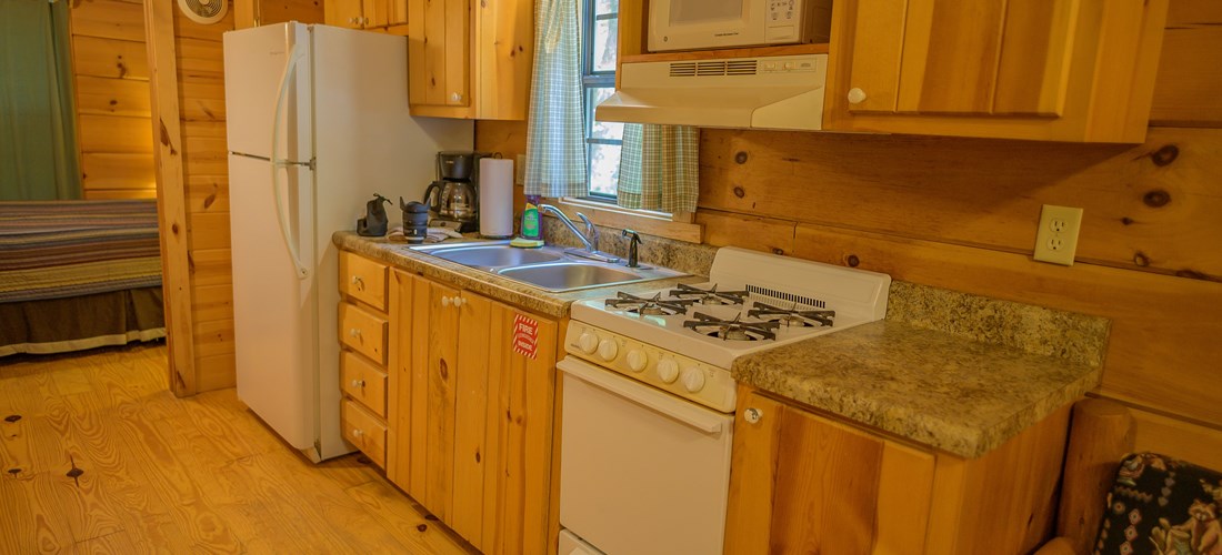 Galley Style kitchen of Deluxe Cabin. Full Fridge, gas stove and oven, microwave and dishes provided