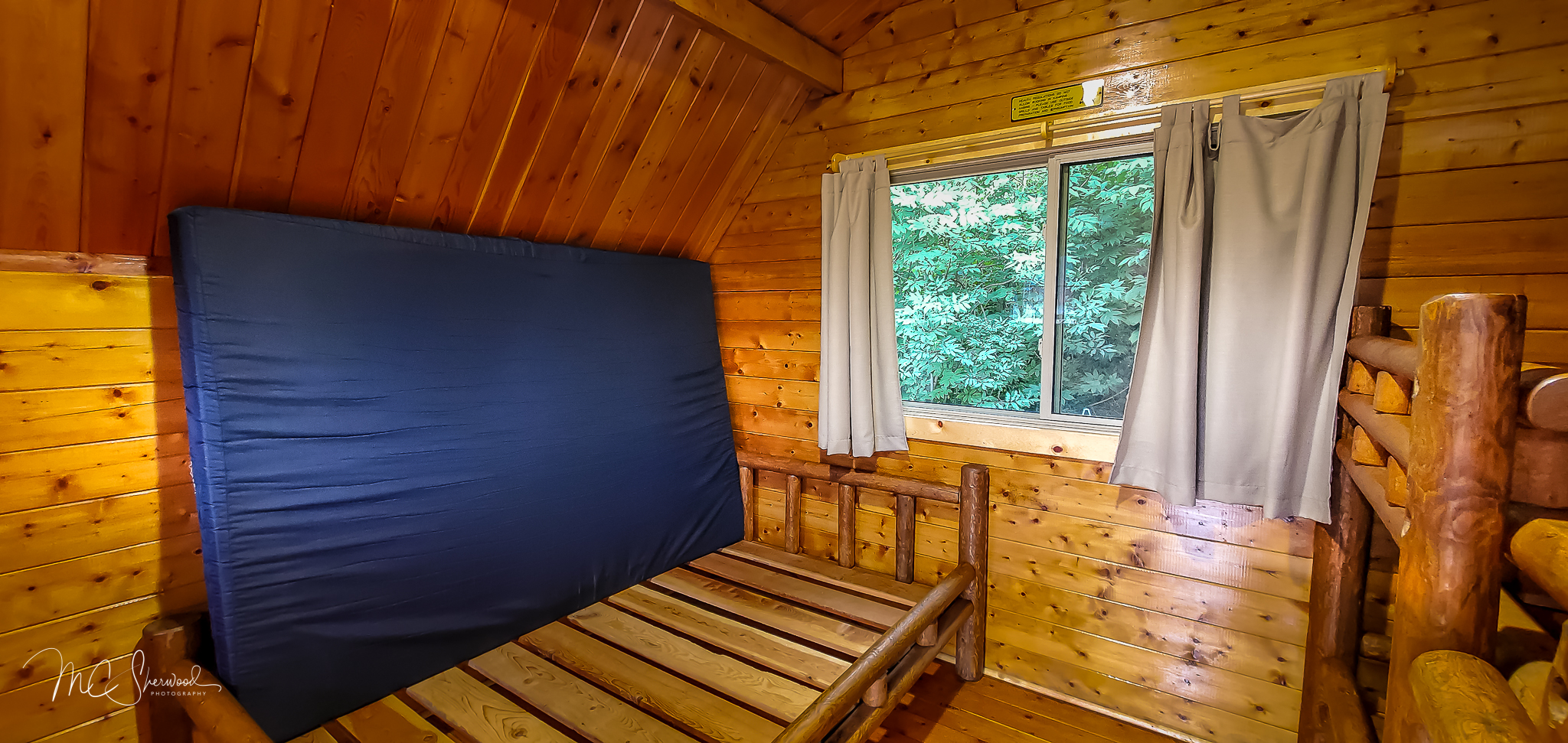 One-room rustic camping cabin interior - full-sized bed
