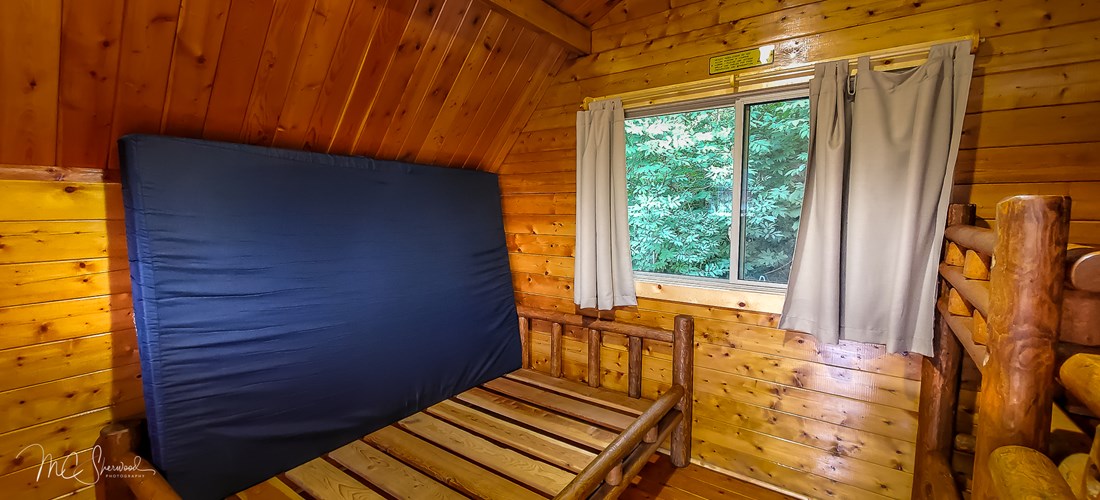 One-room rustic camping cabin interior - full-sized bed