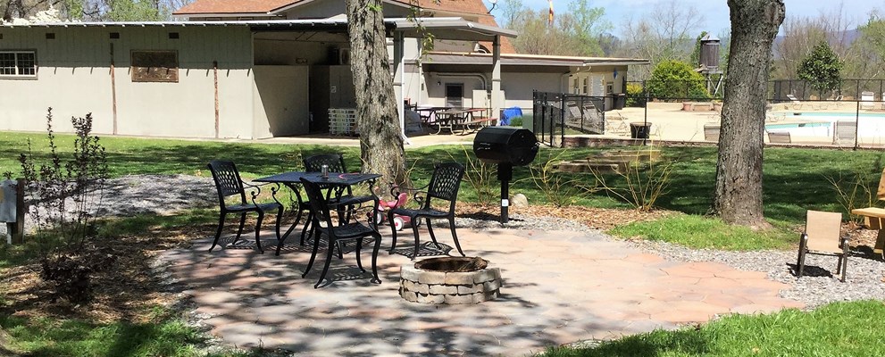 A site with extra amenities, patio, smoker grill, stacked fire ring, and shady.