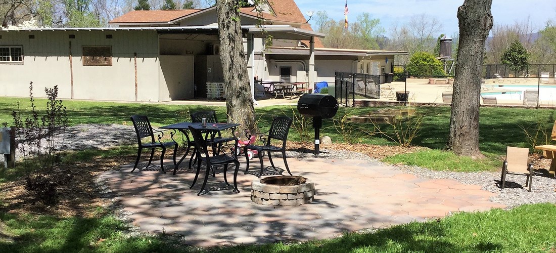 A site with extra amenities, patio, smoker grill, stacked fire ring, and shady.