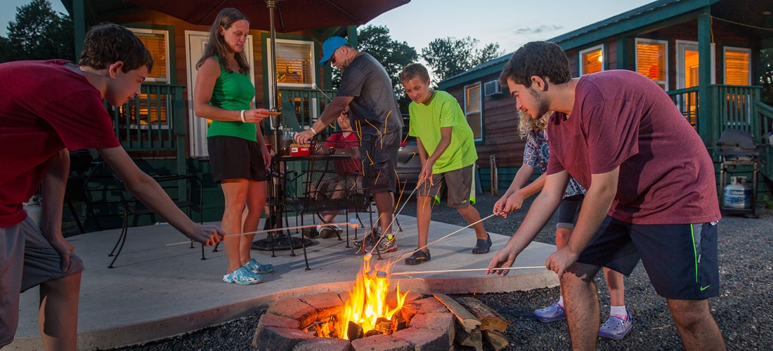 Roasting S'mores Around The Campfire. Fire Ring Provided At Every Site. Waterfront Studio Cabins. Sleeps 4.