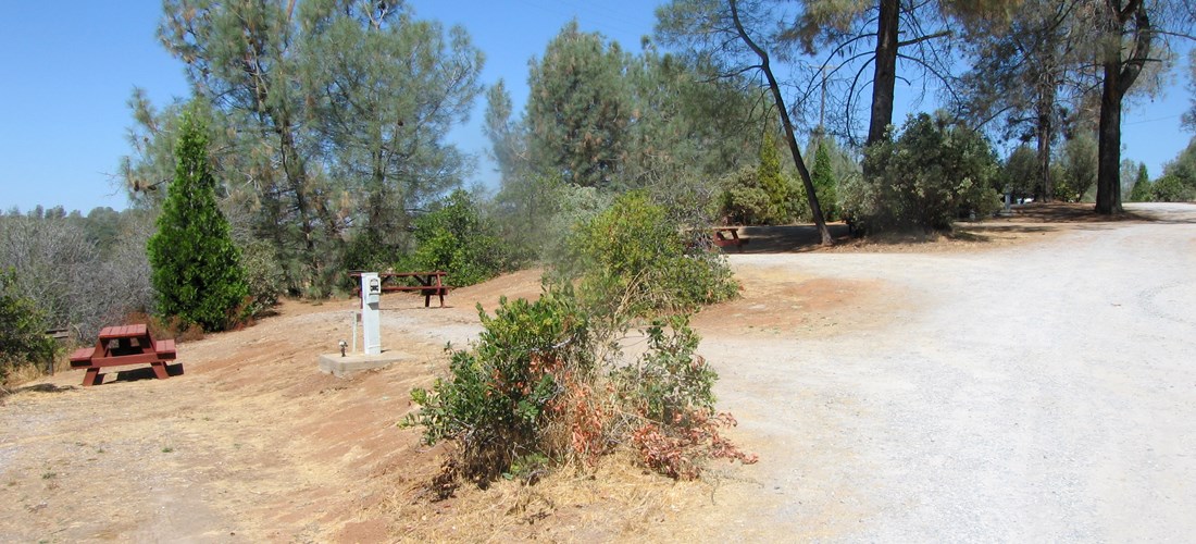 Our water and electric 30 amp pull in sites have are located furthest from the freeway along our back fence line and have a view of the valley. It features a picnic table, bbq grill, wifi access, and HD cable tv. Pictured is site 59.