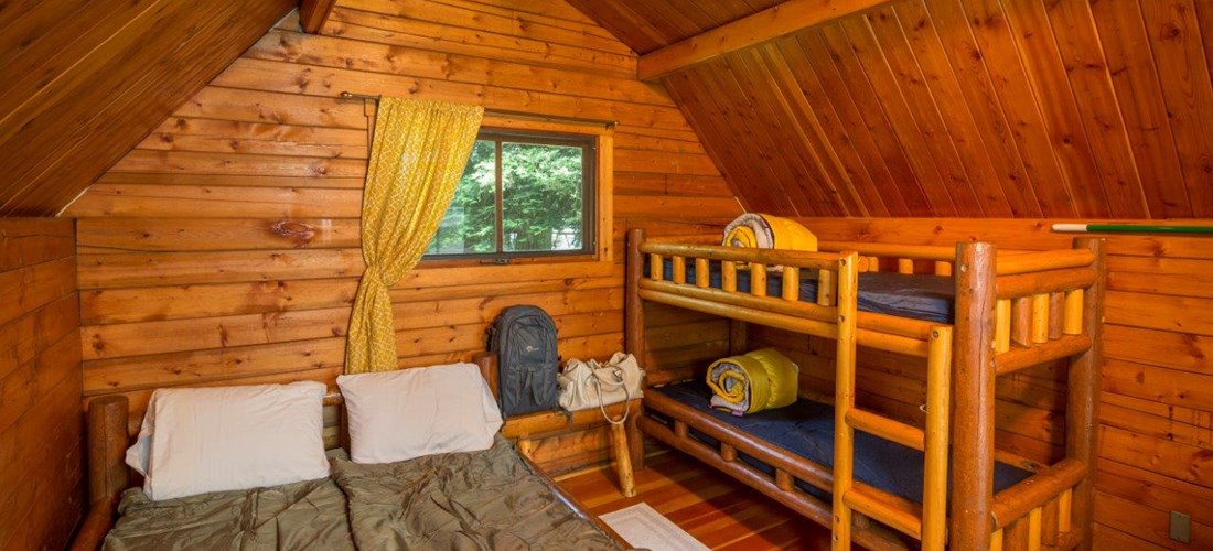 Inside of our camping cabins(linens/sleeping bags not included).  A full size bed and a set up twin bunk beds, TV with cable.  A fire ring, picnic table and parking for 1 vehicle at each cabin site.