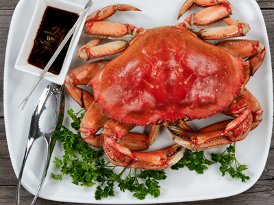 Freshly cooked Dungeness crab served on a plate with dipping sauce and parsley garnish in Valdez.