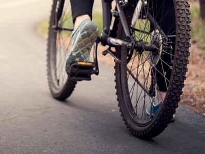 Cyclist riding a mountain bike on a paved path near Valdez KOA Journey.
