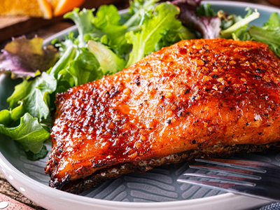 Freshly grilled salmon fillet served on a bed of mixed greens with a side of fork in Valdez.
