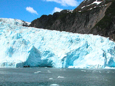 Bright blue face of Worthington Glacier with rocky mountain backdrop near Valdez KOA Journey.