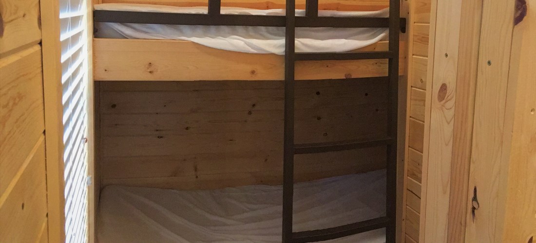 Twin bunk set in separate bedroom with sliding door.