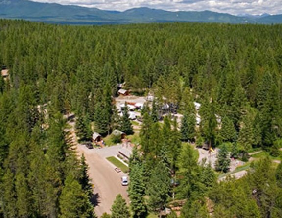 This aerial view of the Whitefish KOA shows the surrounding forest as well as Big Mountain and Glacier Park in the background.