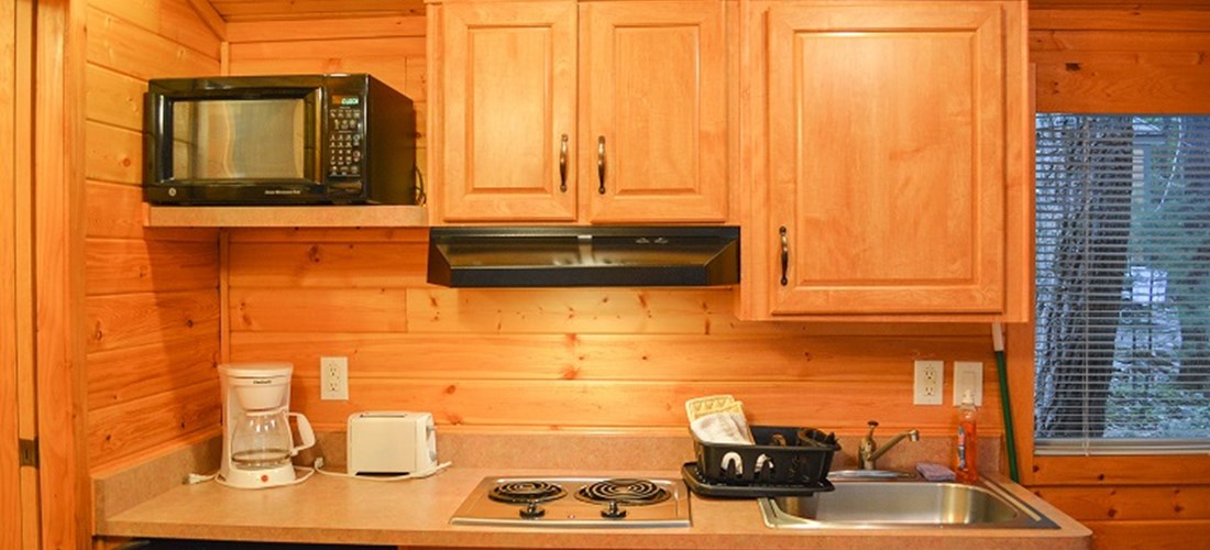 The Deluxe Cabin comes with a mini fridge, stove, toaster, microwave, and kitchenware.