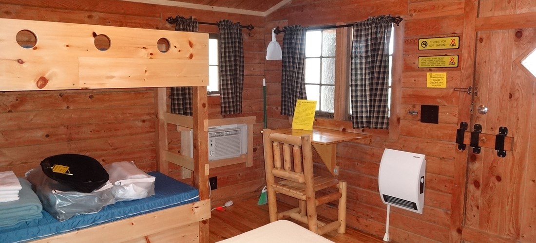The interior of our Camping Cabin consists of a double bed, bunks, and is all 1 room. AC & Heat is included.