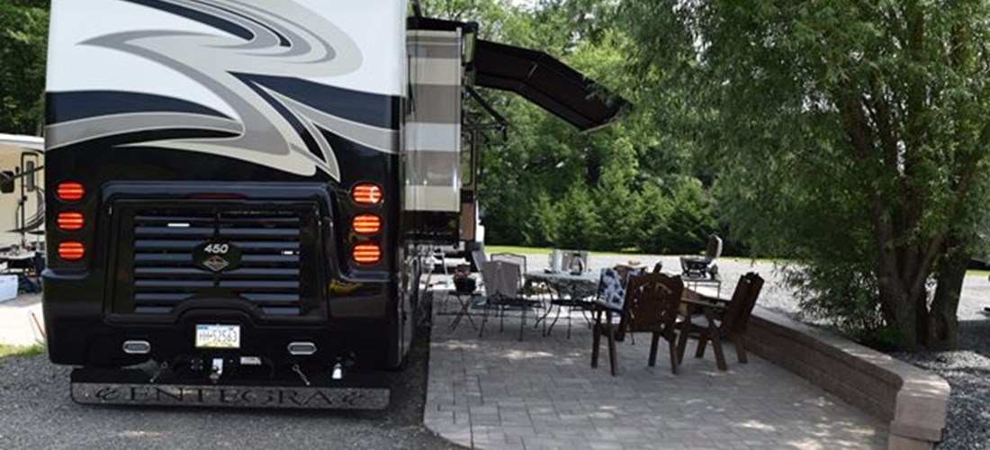 Deluxe Patio Pull Thru Site. Spacious site combined with a beautiful patio, fire pit and outdoor furniture make for a great outdoor experience. 50/30amp elec. Non wooded.