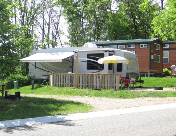 Our deluxe full hookup, back-in site sits across from the pool and next to one of our beautiful deluxe loft cabins.  Cement pad assures level parking and outdoor furniture awaits your arrival on the patio.  Exclusively for your use during the stay is a propane grill.